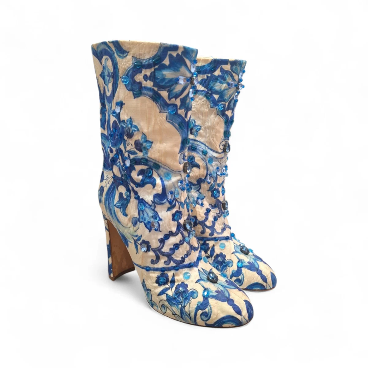 Side profile of Dolce & Gabbana ankle boots featuring a blue and white Majolica tile print brocade, blue crystal embellishments, and a covered block heel.